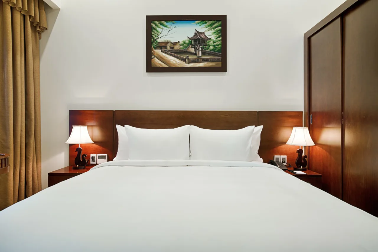 Giường đôi lớn, đèn ngủ hai bên và tranh phong cảnh
