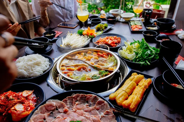 Bàn lẩu với thịt, rau và mì tại nhà hàng trong khu