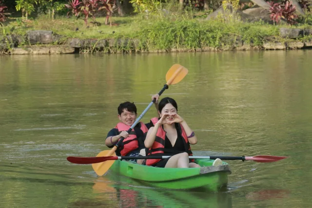 Cặp đôi chèo kayak trên dòng nước giữa vườn cây